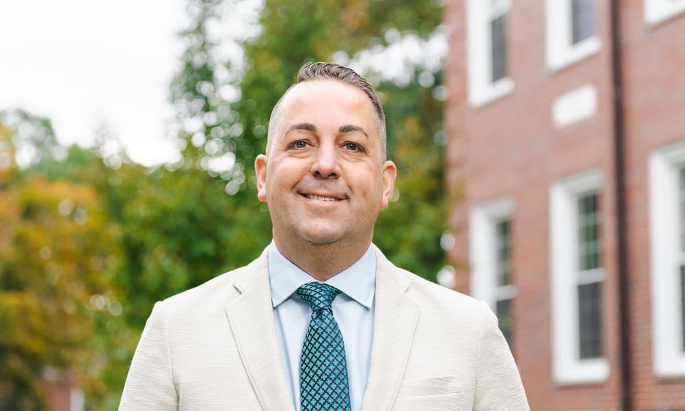 Head shot of Professor Jason Seacat in front of Hermann Hall